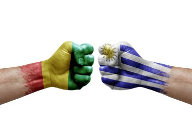 Two hands punch to each others on white background. Country flags painted fists, conflict crisis concept between guinea and uruguay