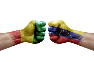 Two hands punch to each others on white background. Country flags painted fists, conflict crisis concept between guinea and venezuela