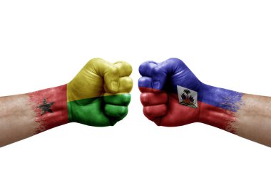 Two hands punch to each others on white background. Country flags painted fists, conflict crisis concept between guinea-bissau and haiti