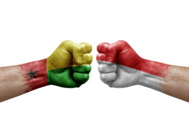 Two hands punch to each others on white background. Country flags painted fists, conflict crisis concept between guinea-bissau and indonesia