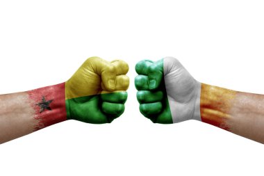 Two hands punch to each others on white background. Country flags painted fists, conflict crisis concept between guinea-bissau and ireland