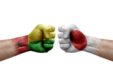 Two hands punch to each others on white background. Country flags painted fists, conflict crisis concept between guinea-bissau and japan