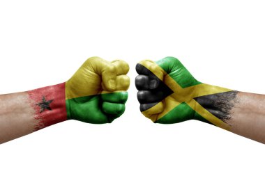 Two hands punch to each others on white background. Country flags painted fists, conflict crisis concept between guinea-bissau and jamaica