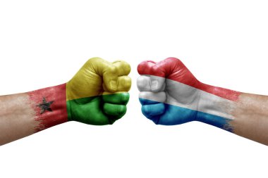 Two hands punch to each others on white background. Country flags painted fists, conflict crisis concept between guinea-bissau and luxembourg