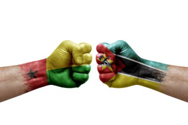 Two hands punch to each others on white background. Country flags painted fists, conflict crisis concept between guinea-bissau and mozambique