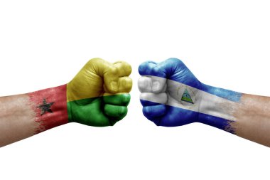 Two hands punch to each others on white background. Country flags painted fists, conflict crisis concept between guinea-bissau and nicaragua