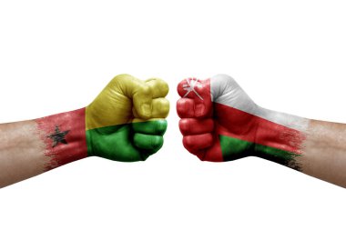 Two hands punch to each others on white background. Country flags painted fists, conflict crisis concept between guinea-bissau and oman