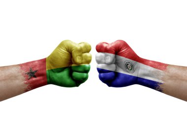 Two hands punch to each others on white background. Country flags painted fists, conflict crisis concept between guinea-bissau and paraguay