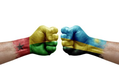 Two hands punch to each others on white background. Country flags painted fists, conflict crisis concept between guinea-bissau and rwanda