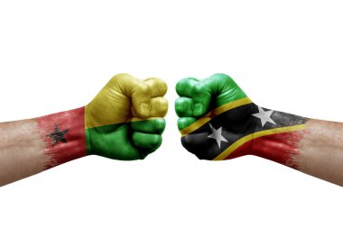 Two hands punch to each others on white background. Country flags painted fists, conflict crisis concept between guinea-bissau and saint kitts and nevis