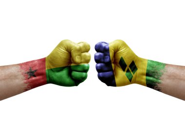 Two hands punch to each others on white background. Country flags painted fists, conflict crisis concept between guinea-bissau and saint vincent and the grenadines