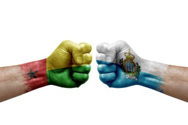 Two hands punch to each others on white background. Country flags painted fists, conflict crisis concept between guinea-bissau and san marino