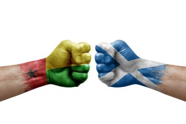 Two hands punch to each others on white background. Country flags painted fists, conflict crisis concept between guinea-bissau and scotland