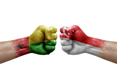 Two hands punch to each others on white background. Country flags painted fists, conflict crisis concept between guinea-bissau and singapore