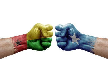 Two hands punch to each others on white background. Country flags painted fists, conflict crisis concept between guinea-bissau and somalia