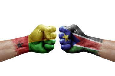 Two hands punch to each others on white background. Country flags painted fists, conflict crisis concept between guinea-bissau and south sudan