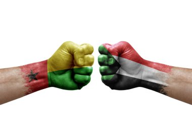 Two hands punch to each others on white background. Country flags painted fists, conflict crisis concept between guinea-bissau and sudan