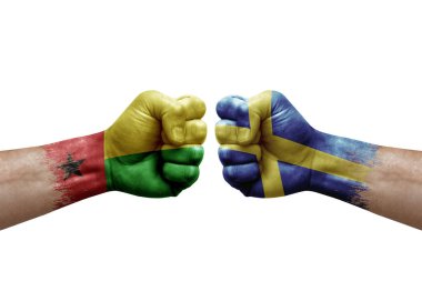 Two hands punch to each others on white background. Country flags painted fists, conflict crisis concept between guinea-bissau and sweden