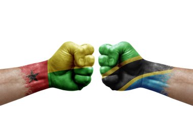 Two hands punch to each others on white background. Country flags painted fists, conflict crisis concept between guinea-bissau and tanzania