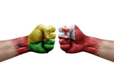 Two hands punch to each others on white background. Country flags painted fists, conflict crisis concept between guinea-bissau and tonga