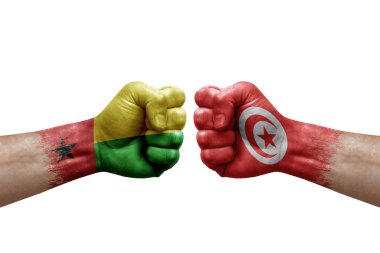 Two hands punch to each others on white background. Country flags painted fists, conflict crisis concept between guinea-bissau and tunisia