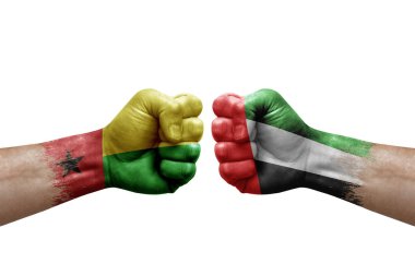 Two hands punch to each others on white background. Country flags painted fists, conflict crisis concept between guinea-bissau and united arab emirates