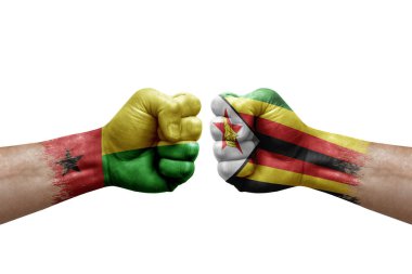 Two hands punch to each others on white background. Country flags painted fists, conflict crisis concept between guinea-bissau and zimbabwe