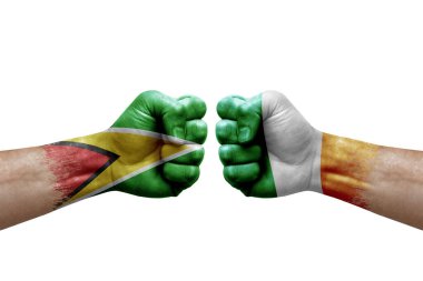 Two hands punch to each others on white background. Country flags painted fists, conflict crisis concept between guyana and ireland