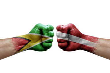 Two hands punch to each others on white background. Country flags painted fists, conflict crisis concept between guyana and latvia