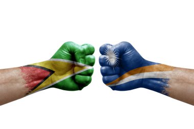 Two hands punch to each others on white background. Country flags painted fists, conflict crisis concept between guyana and marshall islands