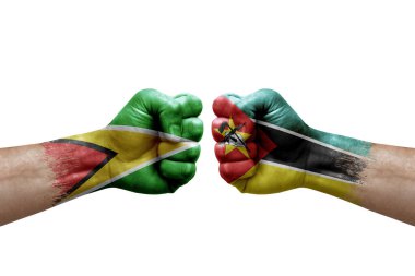 Two hands punch to each others on white background. Country flags painted fists, conflict crisis concept between guyana and mozambique