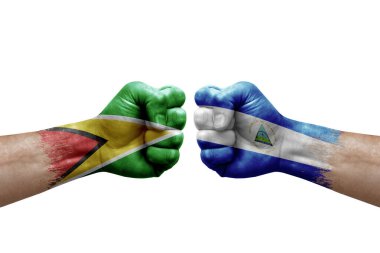 Two hands punch to each others on white background. Country flags painted fists, conflict crisis concept between guyana and nicaragua