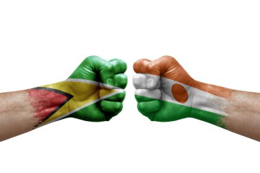 Two hands punch to each others on white background. Country flags painted fists, conflict crisis concept between guyana and niger