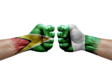 Two hands punch to each others on white background. Country flags painted fists, conflict crisis concept between guyana and nigeria