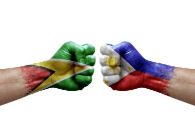 Two hands punch to each others on white background. Country flags painted fists, conflict crisis concept between guyana and philippines