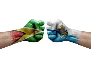 Two hands punch to each others on white background. Country flags painted fists, conflict crisis concept between guyana and san marino
