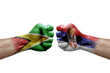 Two hands punch to each others on white background. Country flags painted fists, conflict crisis concept between guyana and serbia