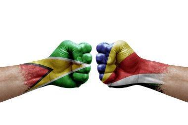 Two hands punch to each others on white background. Country flags painted fists, conflict crisis concept between guyana and seychelles