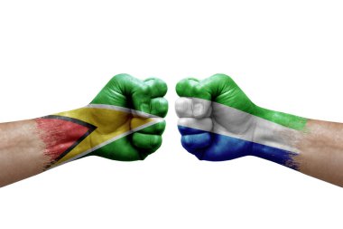 Two hands punch to each others on white background. Country flags painted fists, conflict crisis concept between guyana and sierra leone