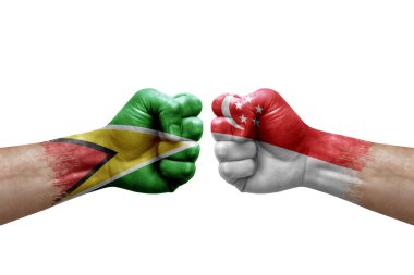 Two hands punch to each others on white background. Country flags painted fists, conflict crisis concept between guyana and singapore