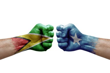Two hands punch to each others on white background. Country flags painted fists, conflict crisis concept between guyana and somalia