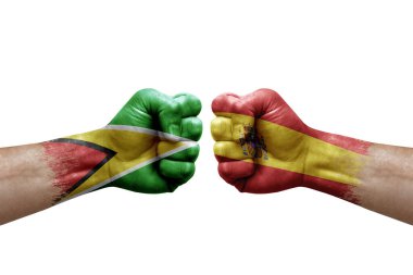 Two hands punch to each others on white background. Country flags painted fists, conflict crisis concept between guyana and spain