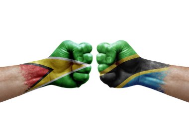 Two hands punch to each others on white background. Country flags painted fists, conflict crisis concept between guyana and tanzania