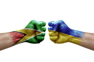 Two hands punch to each others on white background. Country flags painted fists, conflict crisis concept between guyana and ukraine