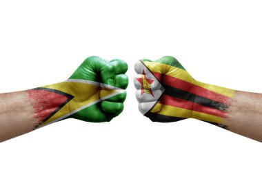 Two hands punch to each others on white background. Country flags painted fists, conflict crisis concept between guyana and zimbabwe