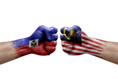 Two hands punch to each others on white background. Country flags painted fists, conflict crisis concept between haiti and malaysia