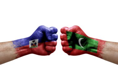 Two hands punch to each others on white background. Country flags painted fists, conflict crisis concept between haiti and maldives