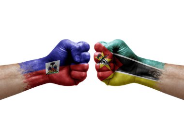 Two hands punch to each others on white background. Country flags painted fists, conflict crisis concept between haiti and mozambique
