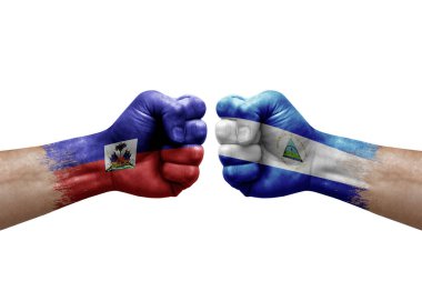 Two hands punch to each others on white background. Country flags painted fists, conflict crisis concept between haiti and nicaragua