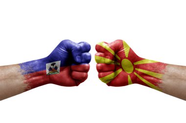 Two hands punch to each others on white background. Country flags painted fists, conflict crisis concept between haiti and north macedonia